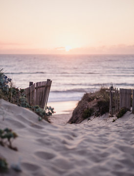 Beach path leading towards the sun setting below the sea