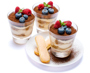 Frame made of Classic tiramisu dessert with blueberries and raspberries in a glass and savoiardi cookies isolated on a white with clipping path