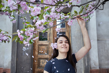 Young woman posing on the background of the old wooden door and blooming sakura