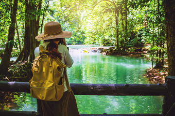 Asian woman travel nature. Girls walking on a wooden bridge. Travel nature in the green forest and enjoy the view of the waterfall. Tourism hiking nature study. © last19