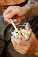 Plastic glass with granola in a man's hand. Summer food in a cafe. Healthy breakfast