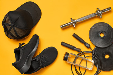 Close-up studio shot of a gym accessories on a yellow background. Top view, flat lay.