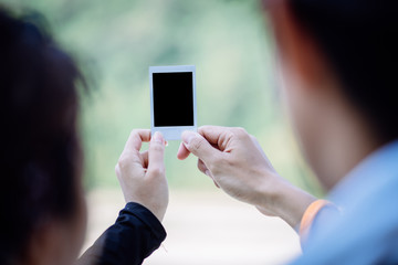 Couple holding blank instant photo frame on the beach.