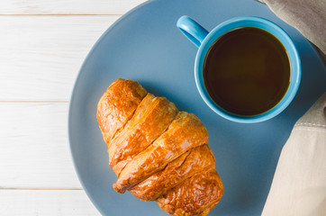Fresh ruddy croissants with berries lie on a wooden table next to fresh black currant berries, red currants