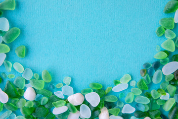 Close up of various sea glass pieces on blue background. Design template. Border frame with copy space for text. Top view, flat lay