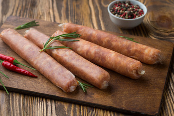Raw sausage with hot  spices on a dark wooden background