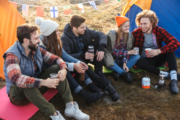 Group of cheerful young friends camping outdoors