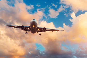 Evening sky with broken beautiful clouds of warm colors and airplane approaching the landing airport.