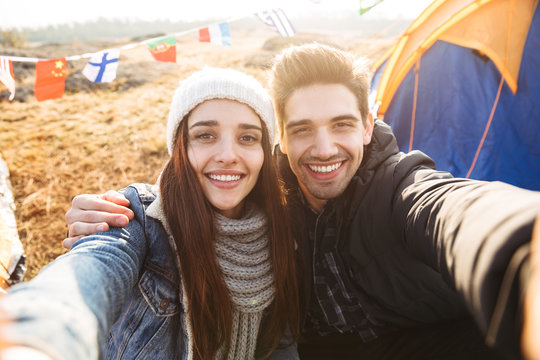 Loving couple outside in free alternative vacation camping over mountains take selfie by camera.