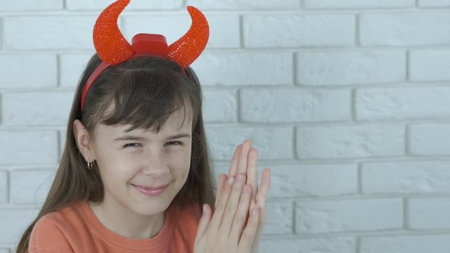 A child with demon horns. Sly little girl in devil horns. Cunning child.