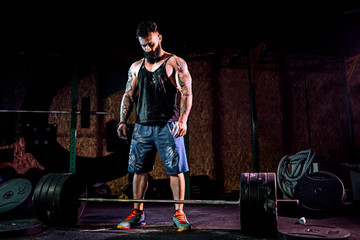 Muscular fitness man preparing to deadlift a barbell in modern fitness center. Functional training....