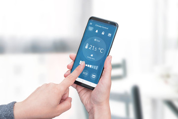 Smart home climate control app on phone display concept. Woman holding a phone and adjust...
