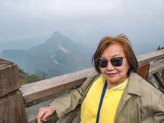 Beautiful senior asia woman on wooden bridge crossing the mountain on tianmen mountain national park at Zhangjiajie city china.landmark of hunan