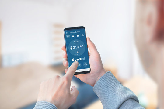 Man use the app to control the climate in the living room. Concept of a modern app with wi-fi control climate devices.