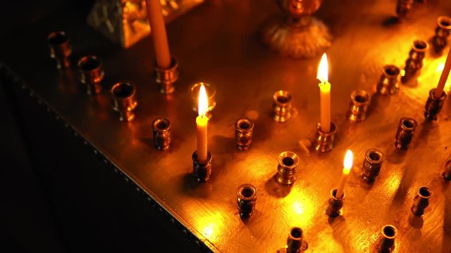 Three burning candles in a large candlestick with many holes for candles, top view