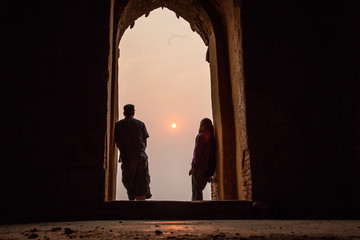 A couple looking at balloons in a temple at the lovely sunrise of Bagan, Myanmar. Vertical photo