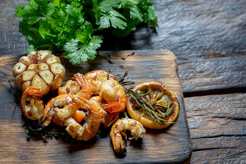 Grill Shrimp BBQ style,ingredient  for dinner on old wooden board. Food background with spiced and lemon, garlic and rosemary . Seafood. Top view.