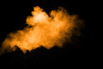 Abstract orange dust explosion on  black background.  Freeze motion of orange powder clouds splash.