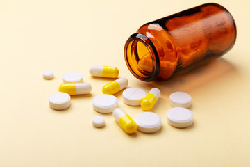 Multicolor tablets and pills capsules from glass bottle on yellow background Heap of assorted various medicine tablets and pills. Health care Close-up Copy space