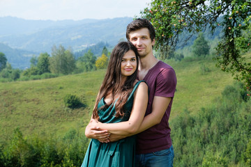 Elegant and beautiful couple on the mountain. Girl in the long green dress with boyfriend.