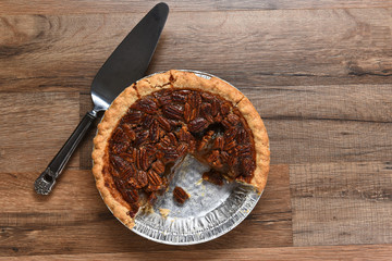 A Thanksgiving holiday pecan pie in tin with piece missing.