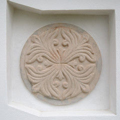Round decorative bas-relief on a white wall.