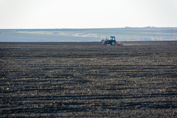 Farm Tractor with plow in a field on a Farm in the sunny day. Farmer in tractor preparing land. It...