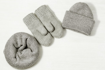 Woolen knitted clothing, wool cap, mittens and scarf. Warm womans winter clothes on white wooden background. Top view. Copy space. Flat lay.