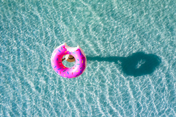 Naklejka premium top aerial view of young woman enjoy swimming on carrying on head floating inflatable tube to sea with cleared water, happy in summertime and vacation or long weekend swimming at sea .