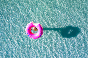 top aerial view of young woman enjoy swimming on carrying on head floating inflatable tube to sea with cleared water, happy in summertime and vacation or long weekend swimming at sea .