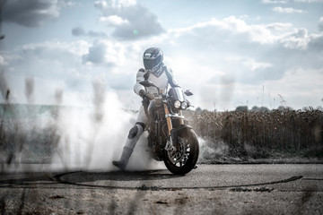Obraz na płótnie Canvas wilder Motorradfahrer lässt die Reifen bei einem Burnout durchdrehen und macht einen Donut