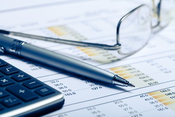 Pen, Eyeglasses and Calculator on Financial Figures