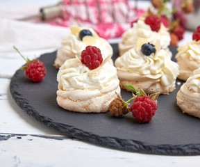 baked round meringues with whipped cream on a black graphite board