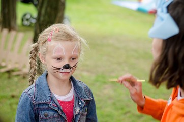 smiling girl with face painting of mouse