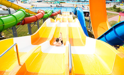 Top view of happy crazy man on top of slide in aqua park - Young people having fun in summer...