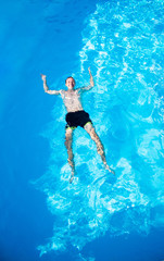 happy man is swimming in pool from top view. Summer vacation