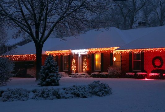 Beautiful Winter Blizzard Evening View. Front Yard Of The Private House Covered By Snow And Decorated For Winter Holiday Season Glowing In The Night. Christmas And New Year Background.