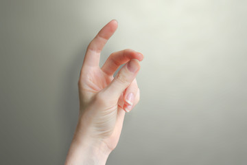 Female hand snap fingers on a grey background