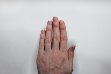 Woman's skinny hand in front of grey background
