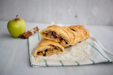 strudel with apple and cinnamon on a light towel, light background