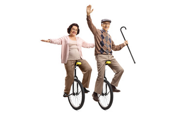 Elderly man holding a walking cane and an elderly woman riding unicycles and smiling © Ljupco Smokovski