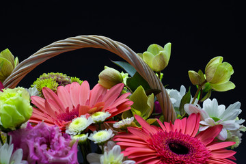 bright flower arrangement in a white basket on a dark background flowers in a wicker basket
