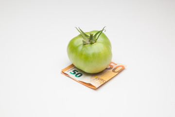 Tomate y monedas al lado, tomate y dinero al lado, el precio del producto. El pprecio de la cosecha, lo que vale la cesta de la compra. Inversión en la agricultura.