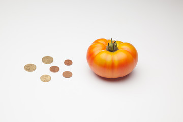 Tomate y monedas al lado, tomate y dinero al lado, el precio del producto. El pprecio de la...