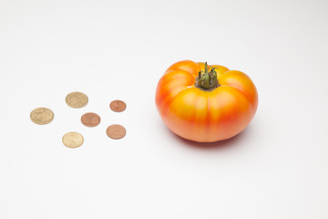 Tomate y monedas al lado, tomate y dinero al lado, el precio del producto. El pprecio de la cosecha, lo que vale la cesta de la compra. Inversión en la agricultura.