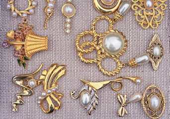 Brooches with pearls on a beige background. Jewelry background for design and decoration.