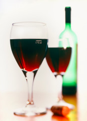 125ml measure of red wine in a set of 2 glasses with a green wine bottle in the background