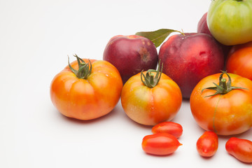 Nectarinas, tomates maduros y tomates cherri sobre un fondo blanco. Los productos han sido traidos de un huerto ecológico, cultivados sin productos químicos ni pesticidas.