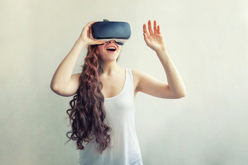 Smile young woman wearing using virtual reality VR glasses helmet headset on white background. Smartphone using with virtual reality goggles. Technology, simulation, hi-tech, videogame concept