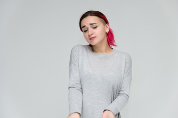 Portrait to the waist of a pretty girl with red hair on a white background in a gray sweater....